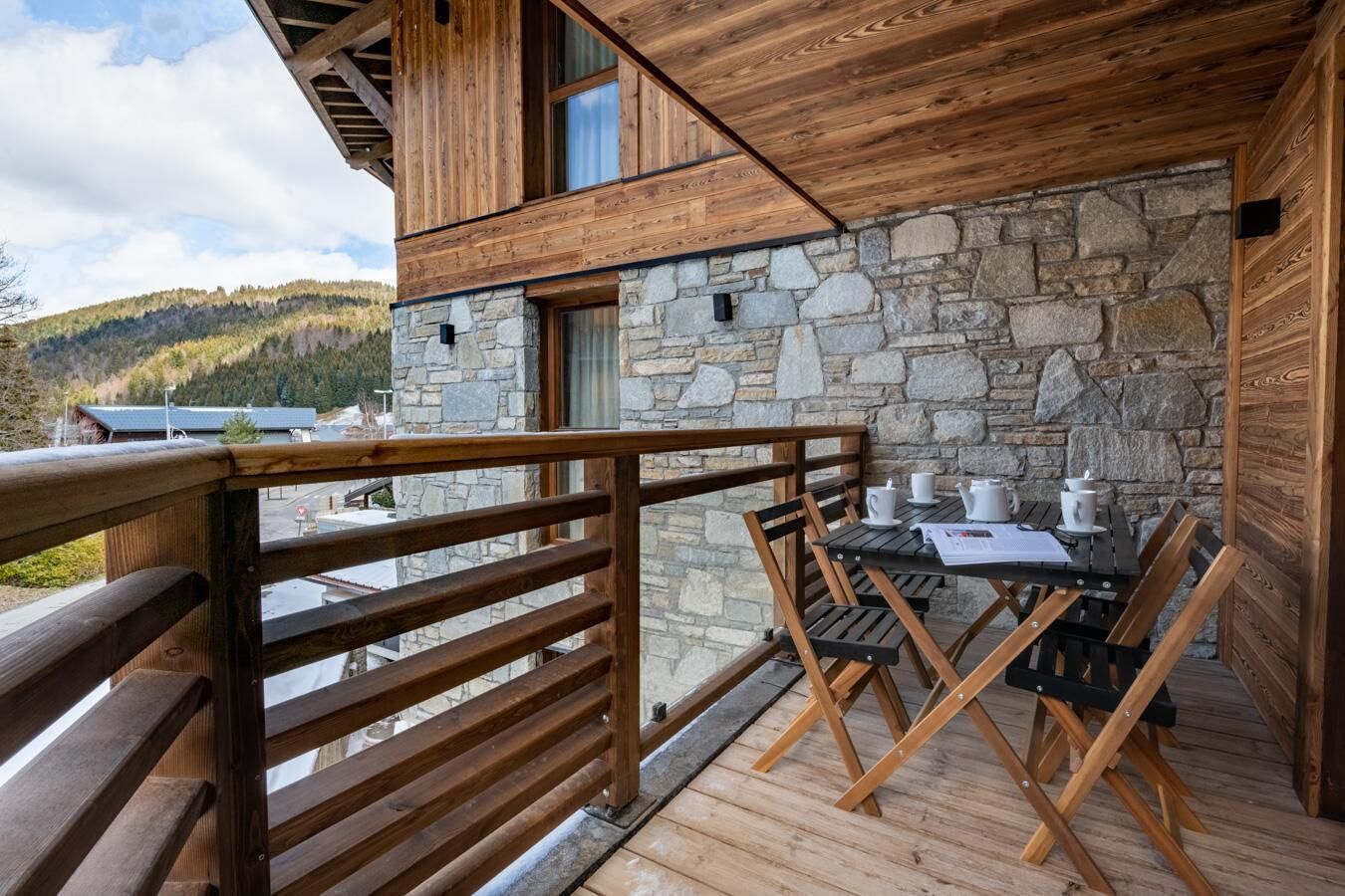 A wooden deck with a stone wall and a wooden railing.