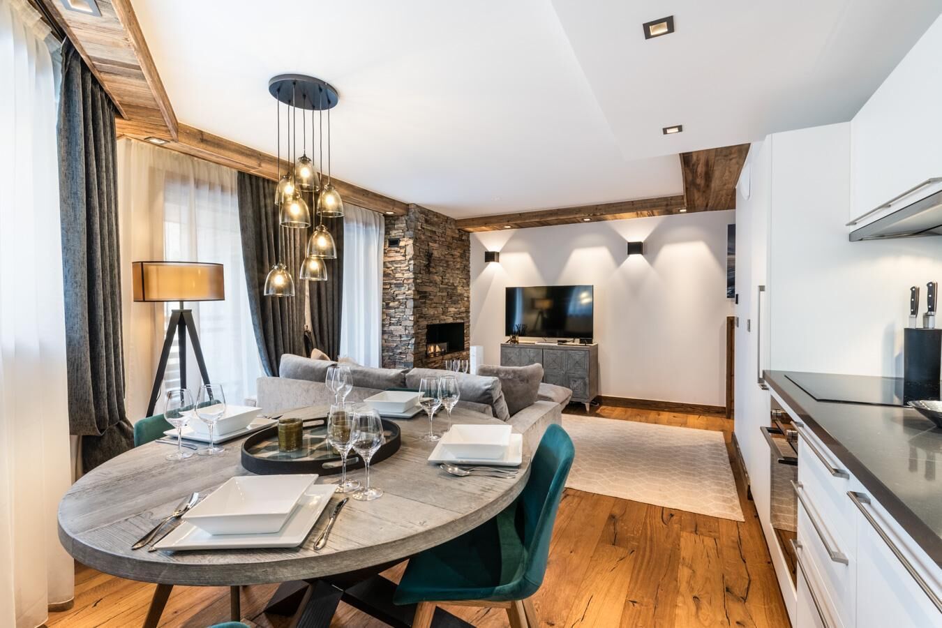 A modern living room with a dining area, stone wall, and a flat-screen TV.