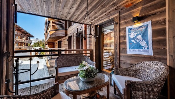 Une cabane en bois dotée d’un balcon, de meubles en osier et d’une affiche représentant une carte.