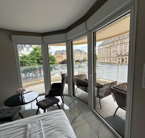 A modern hotel room with a large sliding glass door, a bed, a small table with a vase, and two chairs. - Rock in Share - Le Vigneulles (Metz)