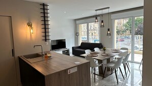 Una cocina moderna con una isla integrada, una zona de comedor con mesa y sillas, y una sala de estar con sofá.