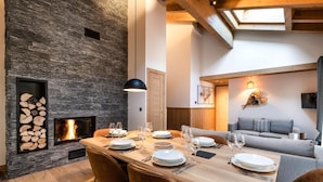 A dining area with a stone wall, a fireplace, and a wooden table set for four. - Wifi, 200m from ski slopes, 4th floor, balcony, fireplace or stove, parking, tv, 82m², Les Gets (Les Gets)