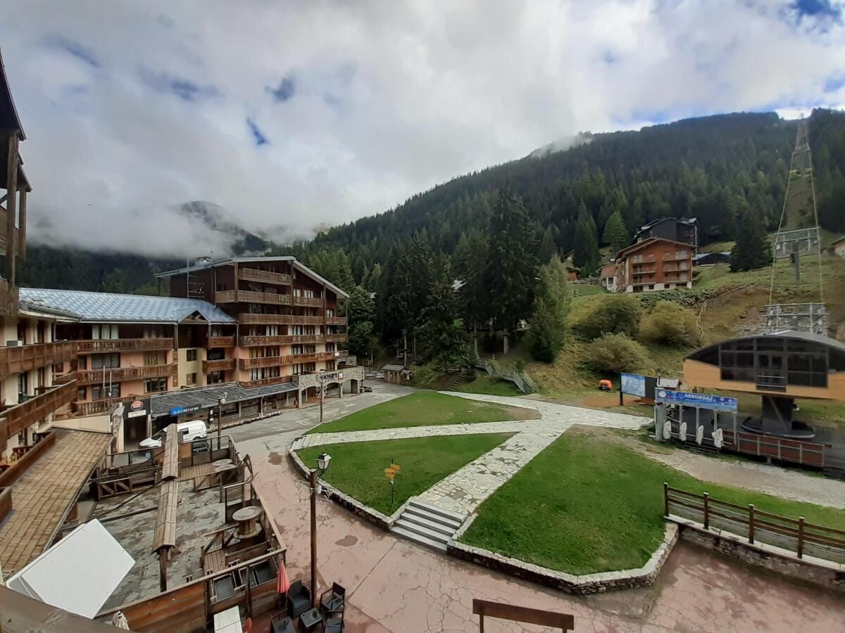 Ein Hotel mit mehreren Etagen, einem zentralen Innenhof mit Brunnen und einer gebirgigen Kulisse.