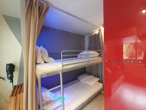 A bunk bed room with a red wall and a ceiling light. - 50m from ski lifts, 3rd floor, view mountain, balcony, tv, ski locker, 20m², Valfréjus (Valfréjus)