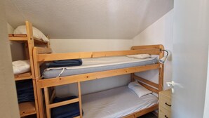 Una cama litera con estructura de madera, un estante inferior y un cajón pequeño.