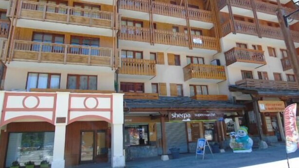 A multi-story wooden building with balconies, a shop named 'Sherpa Supermarket', and a signboard advertising 'Sherpa'. - 4th floor, view valley, balcony, tv, ski locker, 23m², Valfréjus (Valfréjus)
