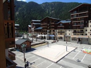 Ein mehrstöckiges Hotel mit Balkonen, einem Parkplatz und einer Bergkulisse.