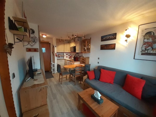 Ein kompakter Wohnraum mit Küchenzeile, Essbereich und einer Sitzecke mit Sofa und Couchtisch.