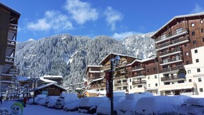 A snow-covered resort with wooden buildings, a ski lift, and a mountain backdrop. - 4th floor, view valley, balcony, tv, ski locker, 23m², Valfréjus (Valfréjus)