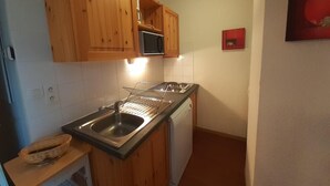 A compact kitchen with wooden cabinets, a microwave, a sink, and a dishwasher. - 180m from ski lifts, floor -2, balcony, tv, ski locker, 32m², Valfréjus (Valfréjus)