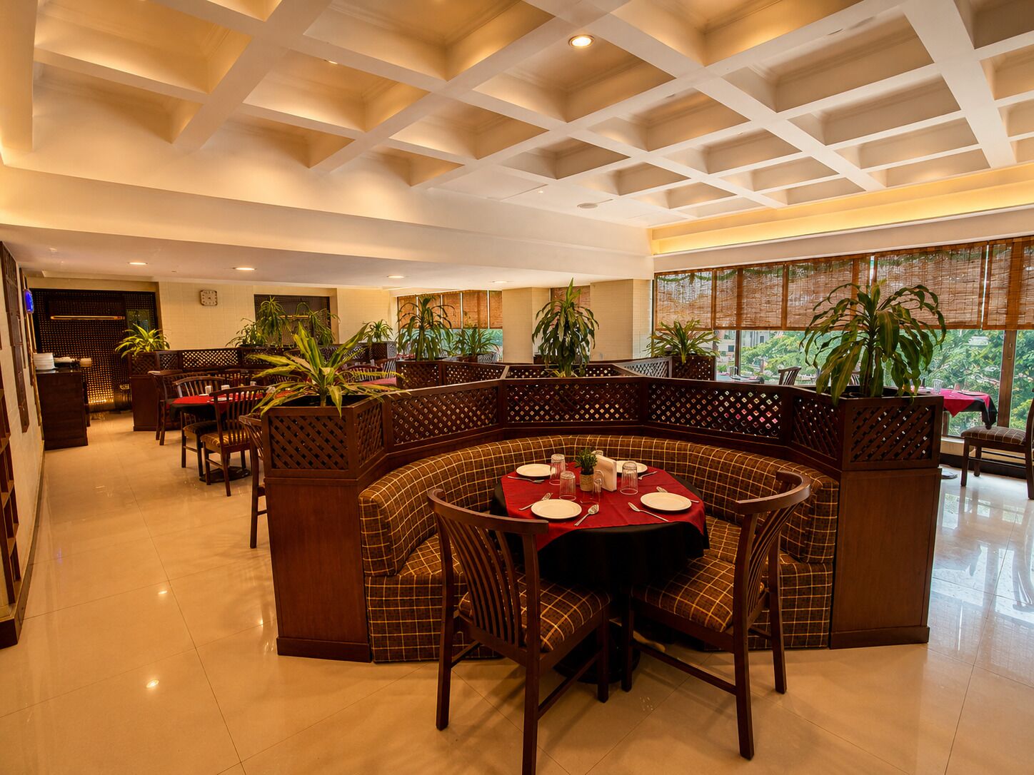Un restaurant avec un plafond haut, des meubles en bois et de grandes fenêtres.