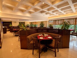 A restaurant with a high ceiling, wooden furniture, and large windows.