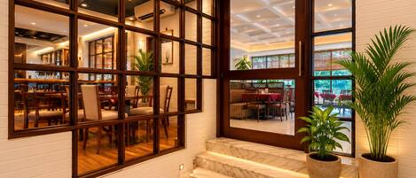 A hotel lobby with a marble staircase, large windows, and indoor plants.