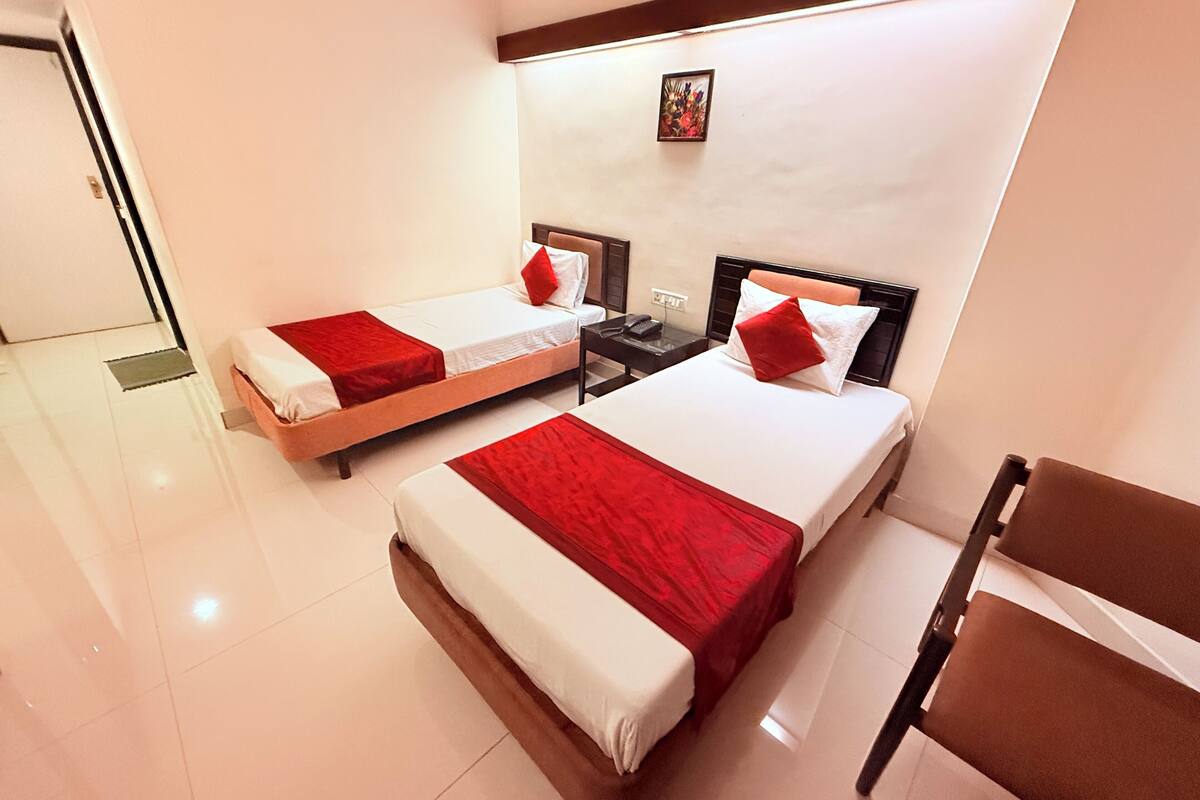 A hotel room with two beds, a nightstand, a chair, and a small painting on the wall.