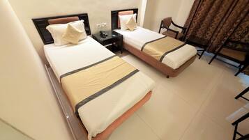 A hotel room with two beds, a desk, a chair, and a window with curtains.
