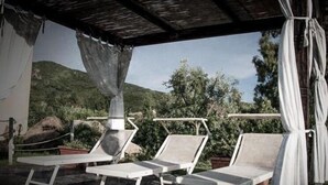 A covered outdoor seating area with lounge chairs and a hammock.