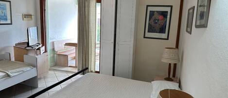A bedroom with two beds, a desk, a chair, a lamp, and a wardrobe.