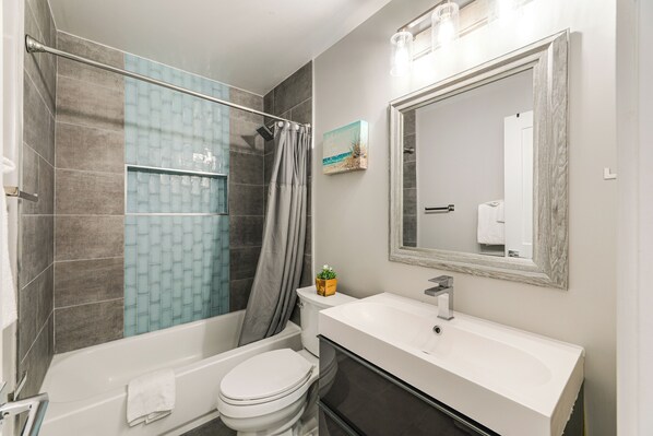 A modern bathroom with a bathtub, toilet, and a large mirror.