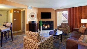 Una sala de estar con chimenea, televisión y muebles estampados.