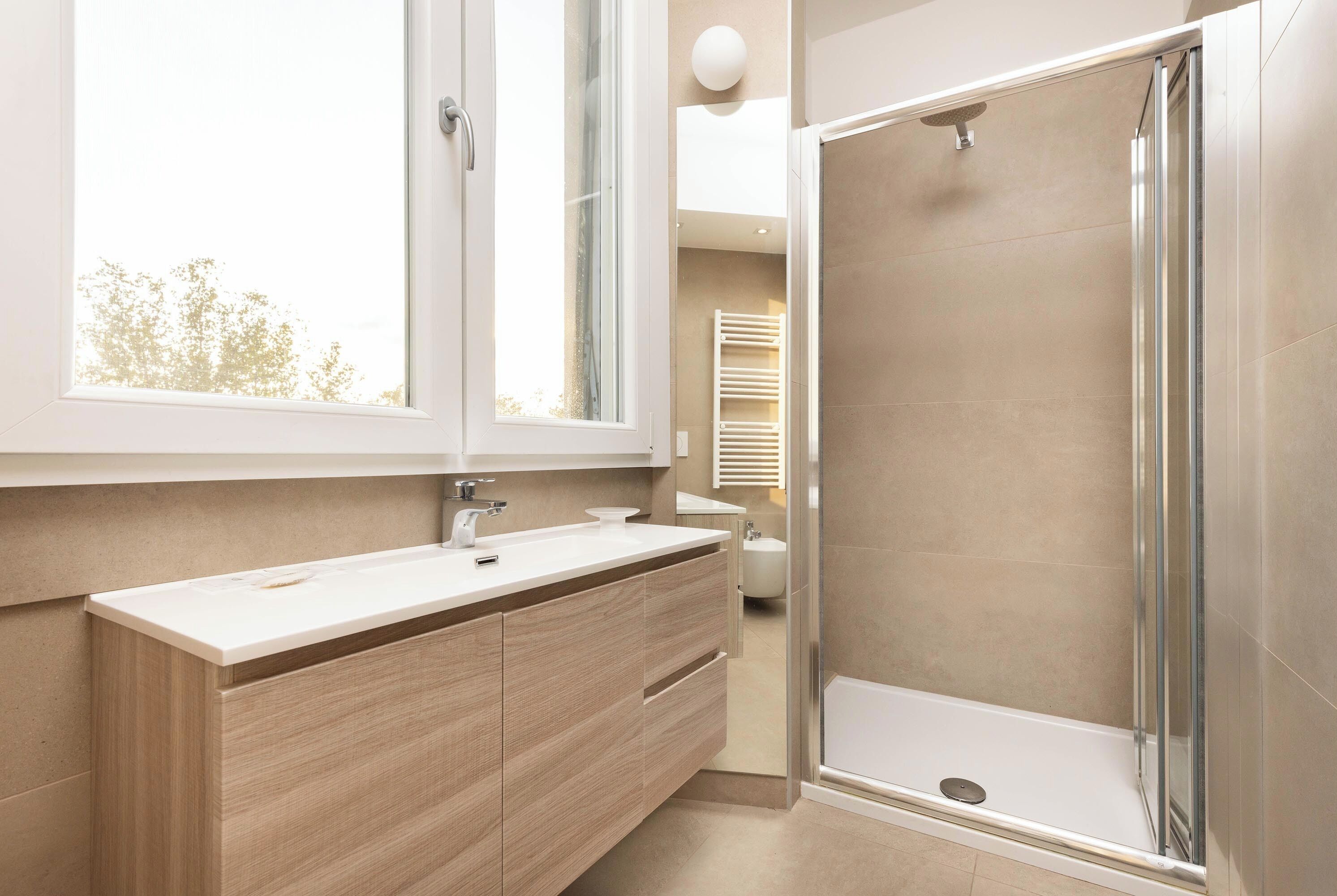Ein modernes Badezimmer mit großem Fenster, Dusche und Waschtisch.