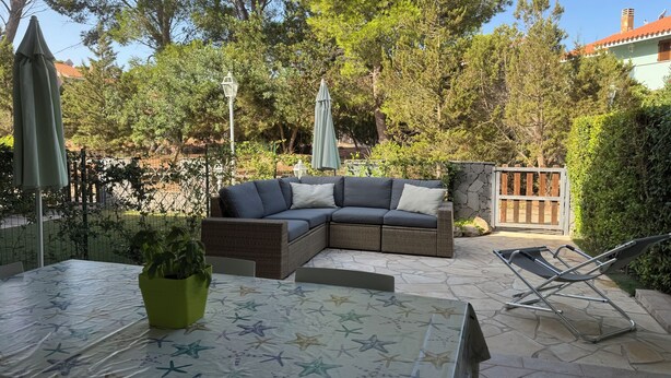 An outdoor patio with a table, a sofa, and a chair.