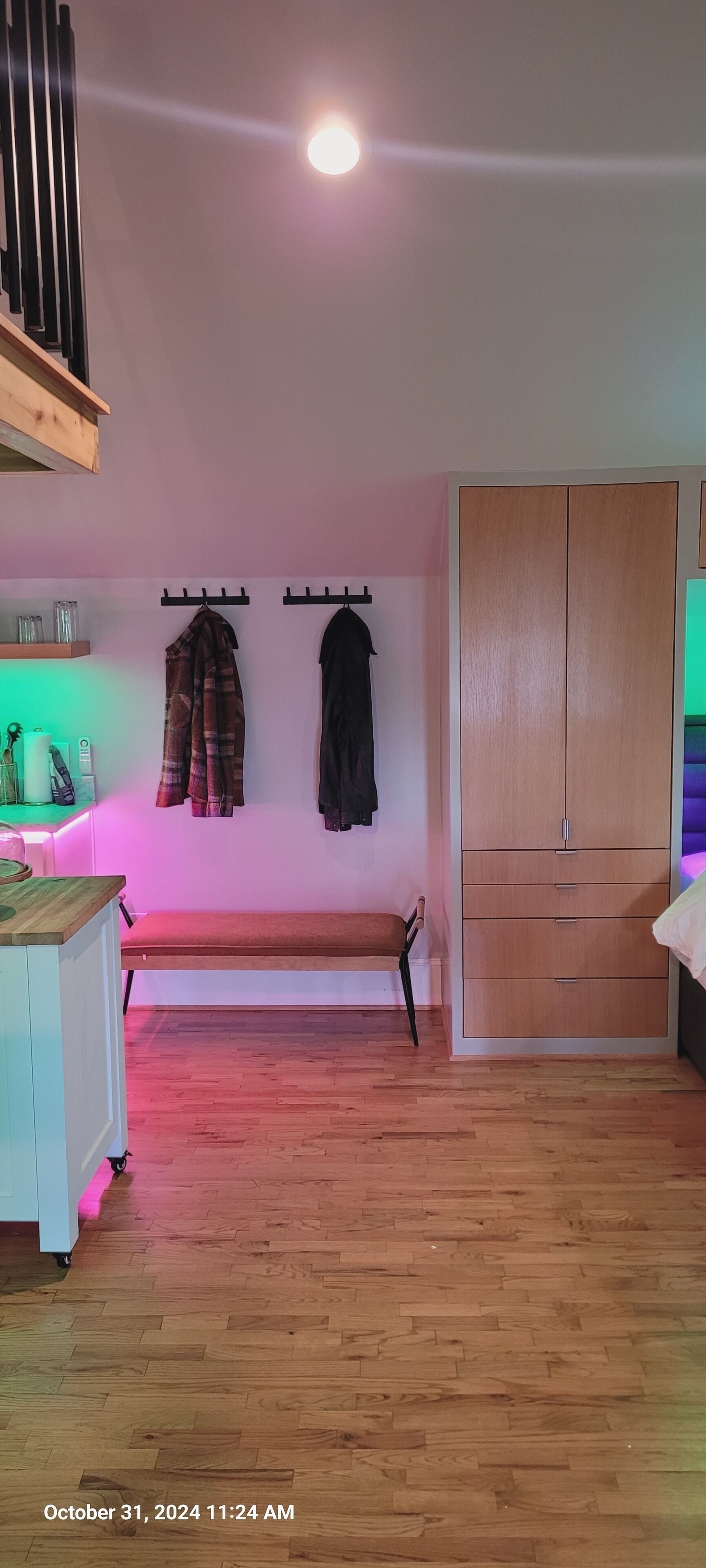 A room with a wooden floor, a bench, a wardrobe, and a wall-mounted coat rack.