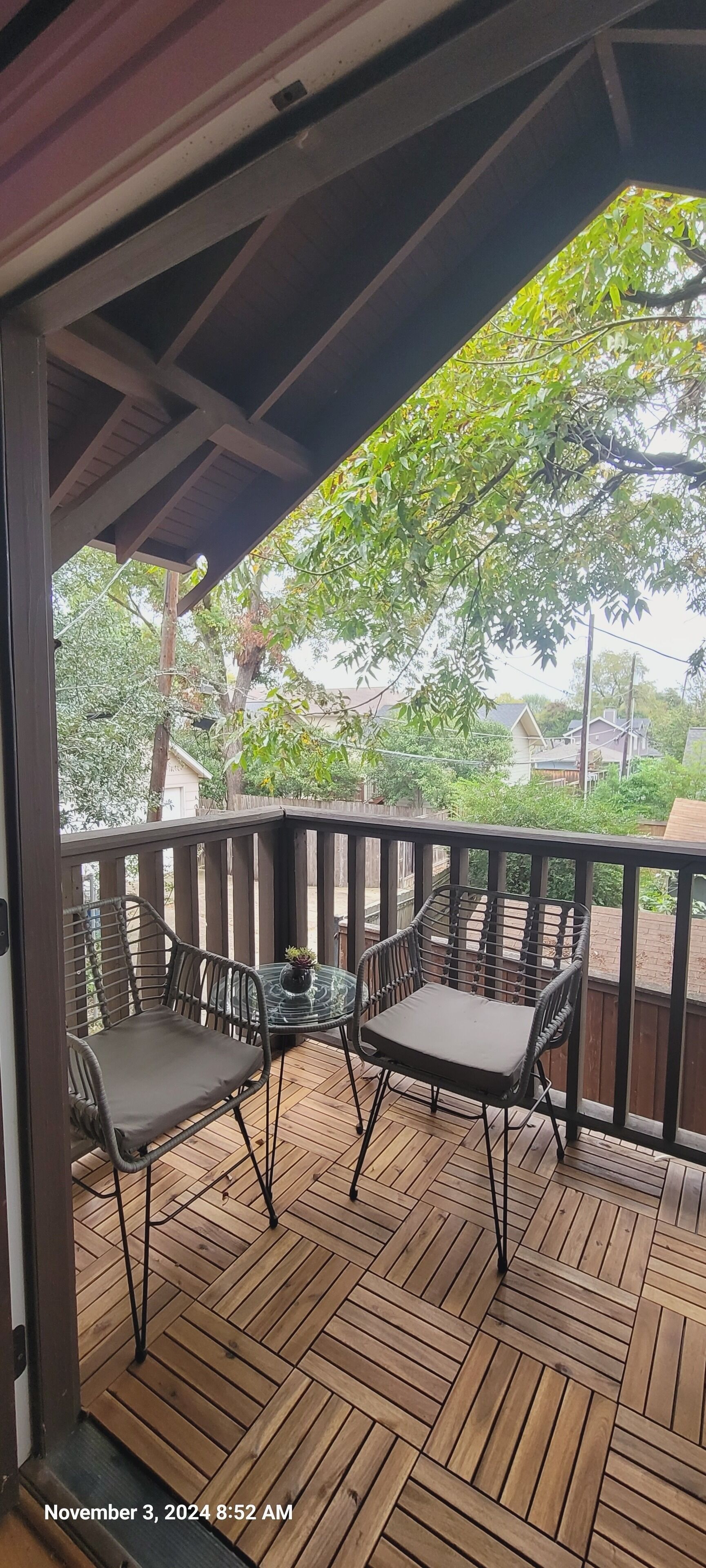 A wooden deck with two chairs and a table, surrounded by a wooden railing.