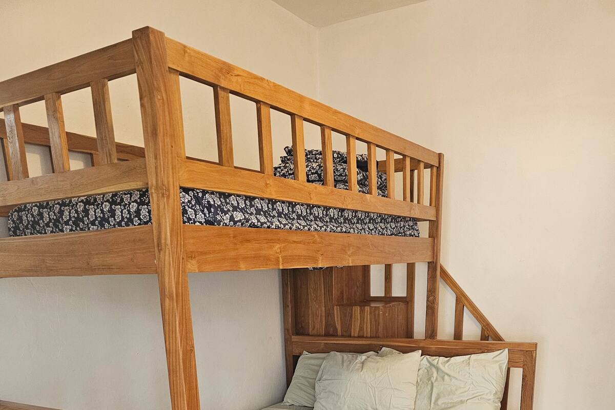 Ein Stockbett mit Holzbettgestell und einem gemusterten Bettbezug.