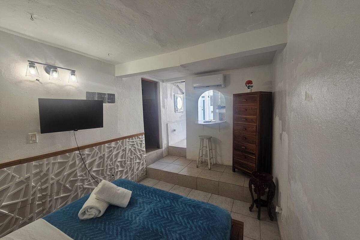 Ein Schlafzimmer mit einem Bett, einem an der Wand befestigten Fernseher und einem Fenster.
