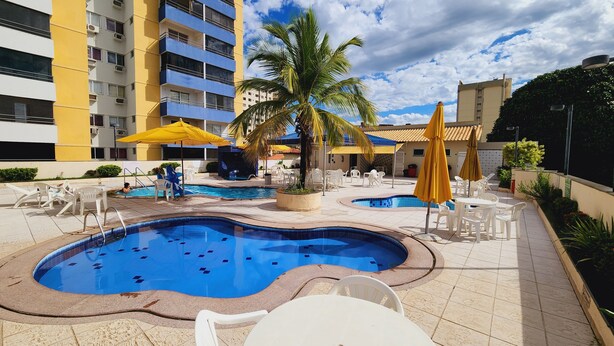 Uma área de piscina com várias piscinas, espreguiçadeiras e guarda-sóis.