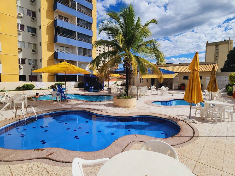 Un área de piscina con varias piscinas, sillas de descanso y sombrillas.