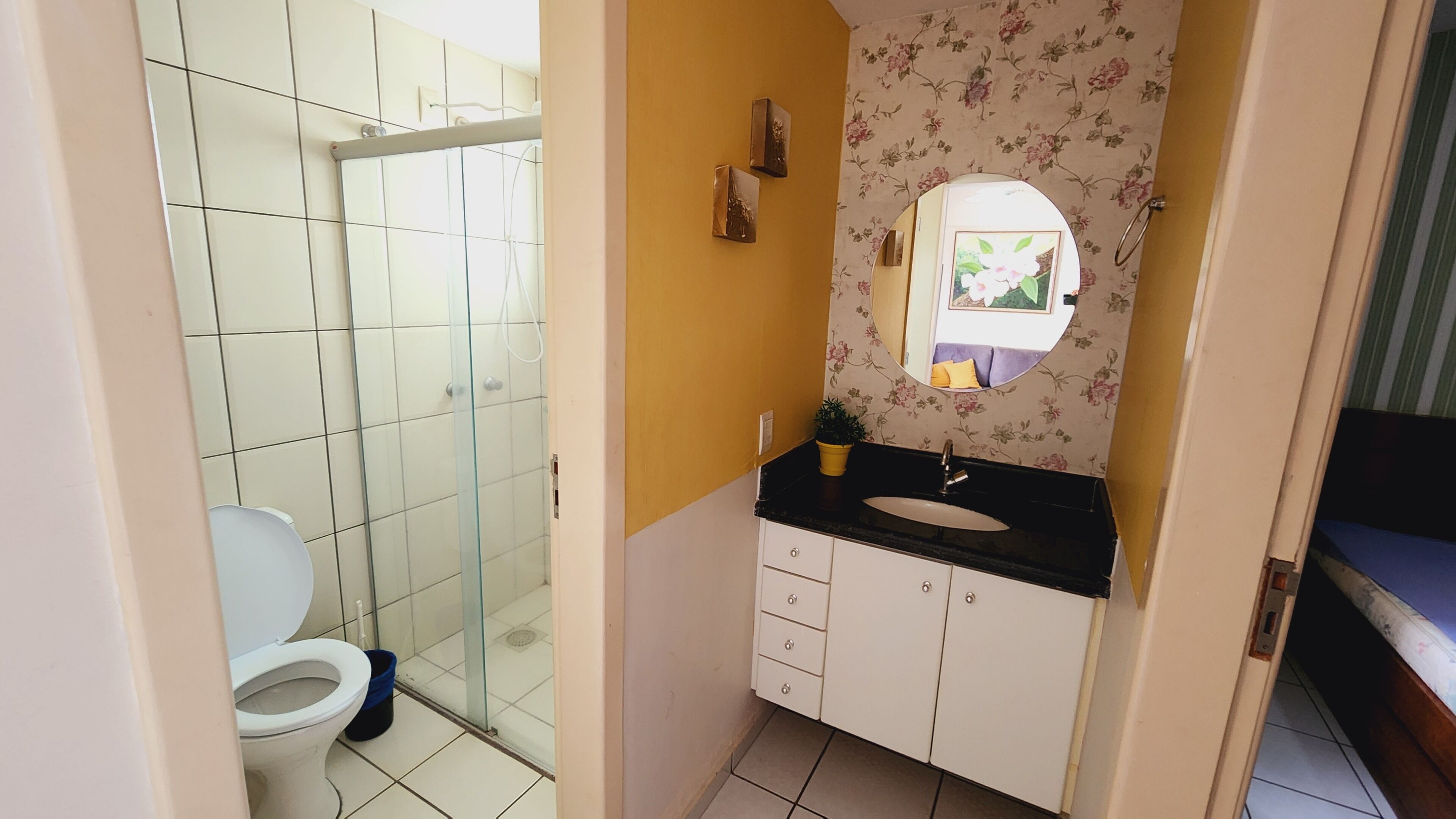 Ein Badezimmer mit Toilette, einer Duschkabine aus Glas, einem Waschbecken mit Spiegel und einem Schrank.