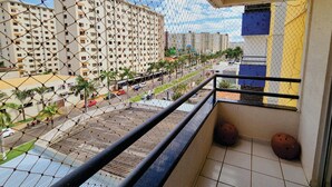 Uma varanda com vista para a paisagem urbana, incluindo edifícios altos e uma estrada com carros.