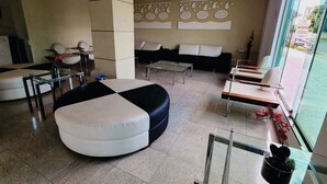 Uma sala de estar moderna com um sofá seccional, uma mesa de centro de vidro e uma área de jantar com uma mesa comprida e cadeiras.