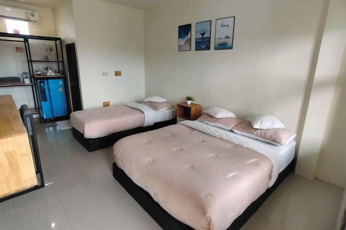 Une chambre d’hôtel avec deux lits, une petite table et un coin cuisine.