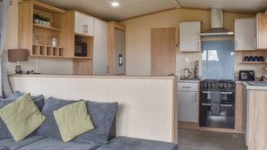 A compact living space with a kitchenette, a sofa with cushions, and a dining area. - 2 bedroom accommodation in Moota, near Cockermouth (Moota, near Cockermouth)