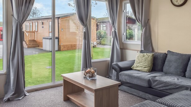 A room with a sofa, a small table, and large windows with curtains. - 2 bedroom accommodation in Moota, near Cockermouth (Moota, near Cockermouth)