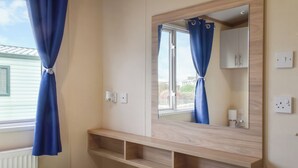 A bedroom with a bed, a mirror, a window with curtains, and a wooden shelf. - 2 bedroom accommodation in Moota, near Cockermouth (Moota, near Cockermouth)