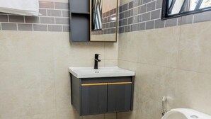 Ein Badezimmer mit einer weißen Toilette, einem Waschbecken mit Spiegel darüber und einem Handtuch an der Wand.
