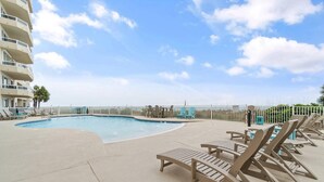 Un espace piscine avec des chaises longues et un bâtiment en arrière-plan.