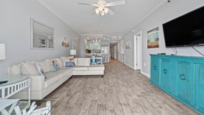 Un salon spacieux avec un canapé blanc, un meuble turquoise et un téléviseur à écran plat.