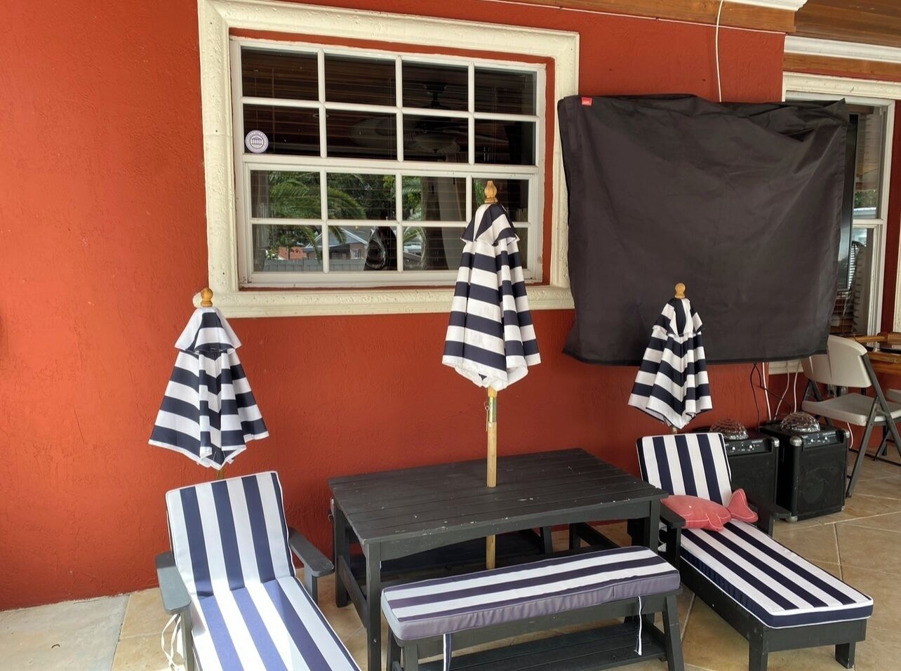 Un patio con sillones reclinables a rayas, una mesa y sombrillas.