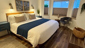 A bedroom with a large bed, bedside tables, a desk, and a chair. - Chelan Condo | Breathtaking Mountain & Lake Views (Chelan)
