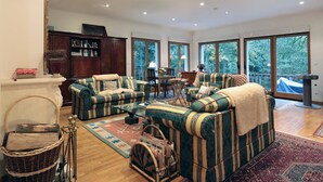 Een ruime woonkamer met gestreepte banken, een glazen salontafel en een groot raam met uitzicht op een balkon.