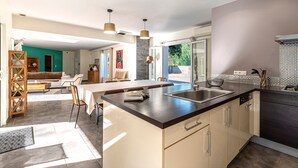 A modern kitchen with a central island, built-in appliances, and a dining area with a view. - Sòle - Peri -  Maison climatisée avec piscine (Peri)