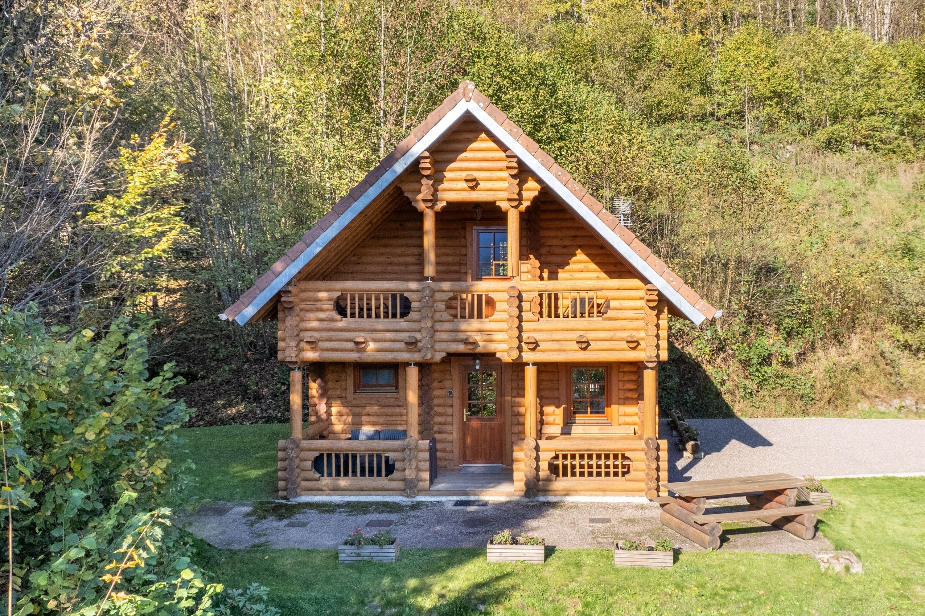 A log cabin with a balcony, a front porch, and a small deck area.
