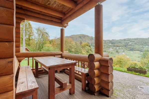 A wooden deck with a wooden table and benches, overlooking a scenic valley. - Chalet des Noisetiers - Magnifique vue montagne (Cornimont)