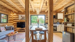 A log cabin interior with a dining area, kitchen, and living room.
