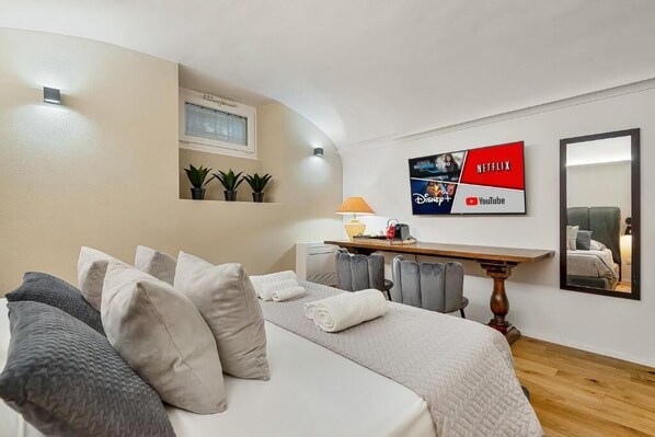 A bedroom with a bed, pillows, a desk, a lamp, and a wall-mounted TV displaying streaming services. - PALAZZO TESTA - LOCAZIONE TURISTICA (Florence)