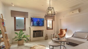 Ein Wohnzimmer mit Kamin, Fernseher, einer Couch, einem Sessel und einem Couchtisch.